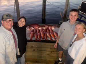 group of 4 people surrounding their redfish catches